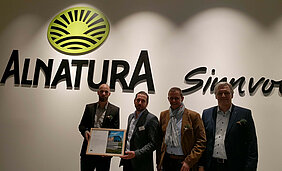 Gruppenfoto von der Eröffnungsfeier mit Rinn-Mitarbeitern und dem Alnatura Betriebsverantwortlichen Expansion und Immobile Thorsten Mergel.