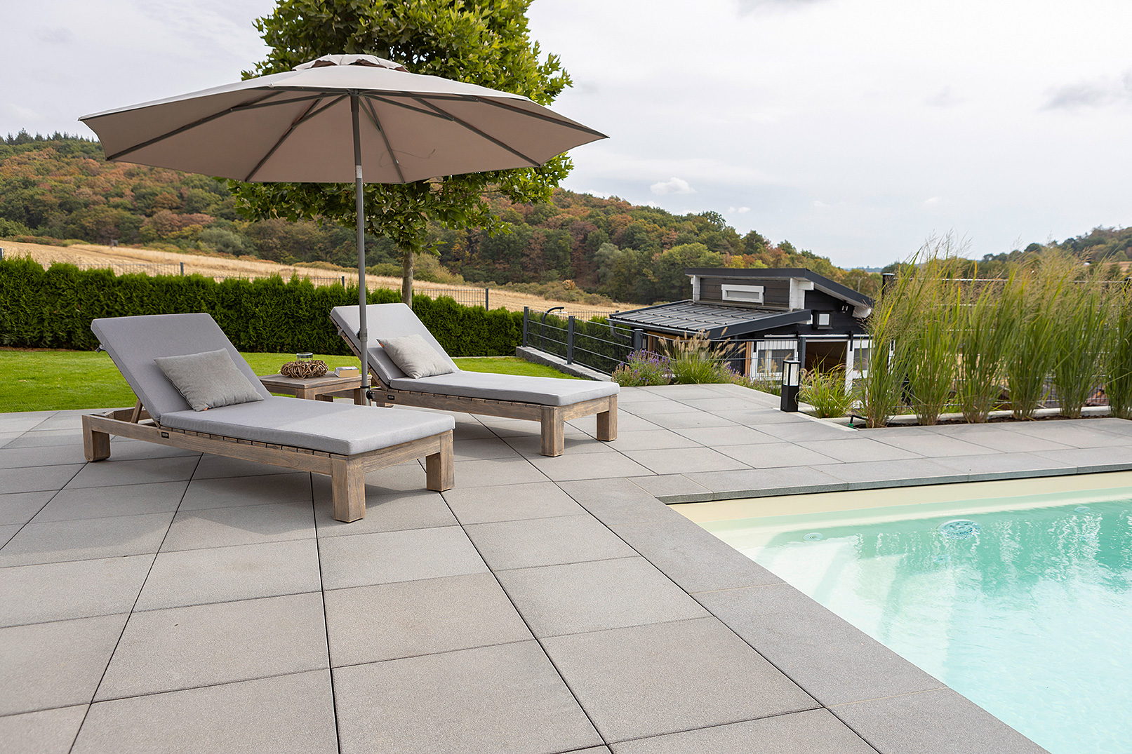 rinn-beton_HAU_220831_ROS-kca_MET7697_s.jpg Pool mit zwei Liegen und Sonnenschirm